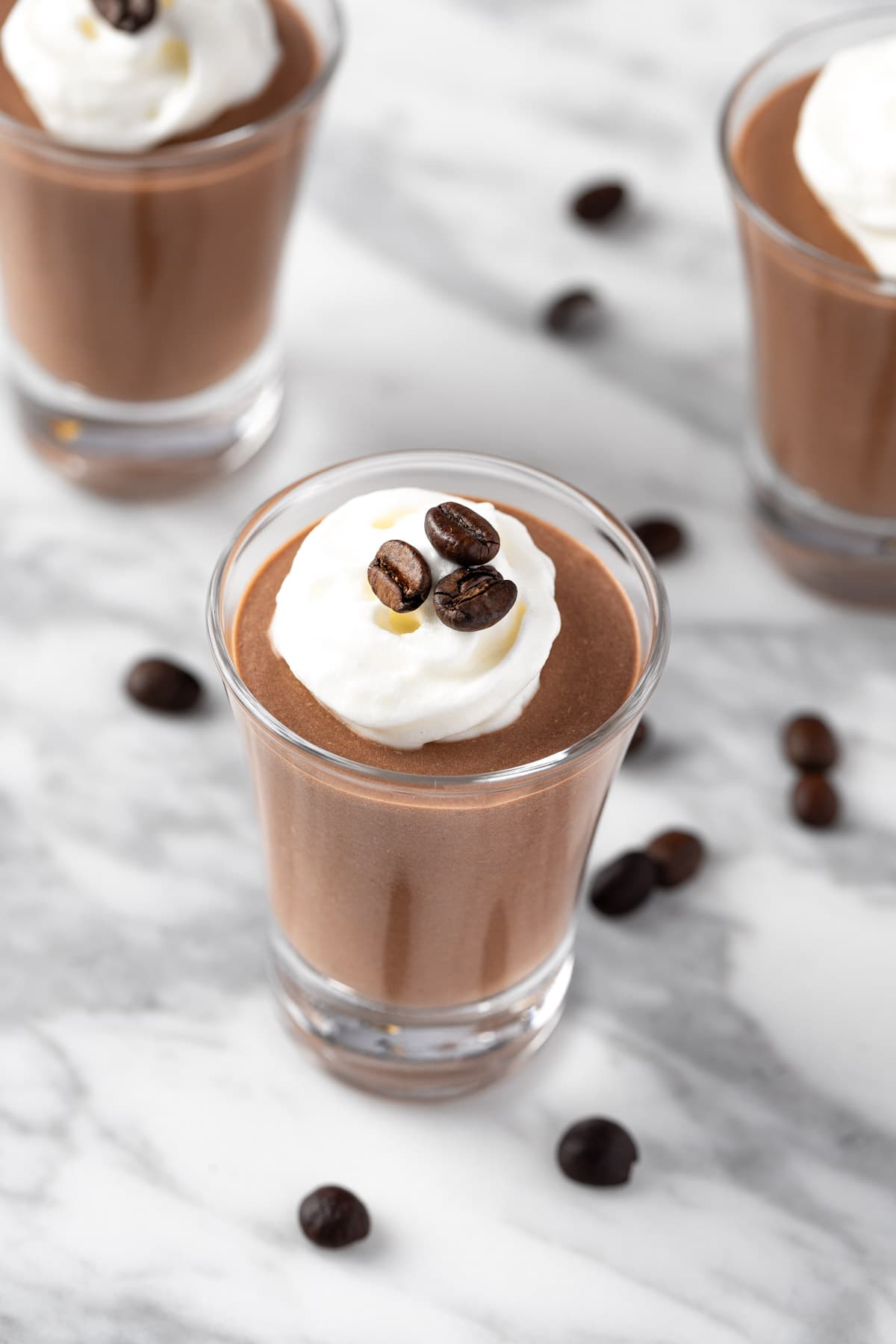 Kahlua Pudding Shots topped with whipped cream and coffee beans.