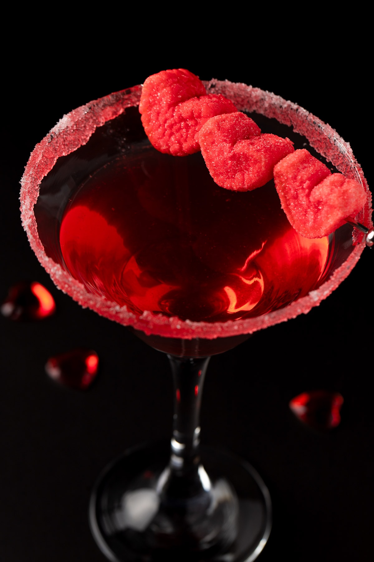 A red Valentine’s love cocktail in a martini glass, on a black background.