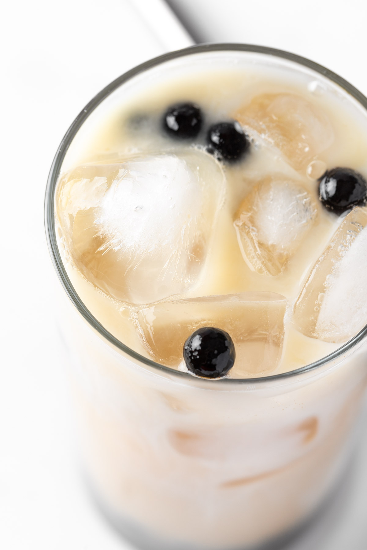 Overhead view of a lychee bubble tea with brown sugar syrup and black tapioca pearls.