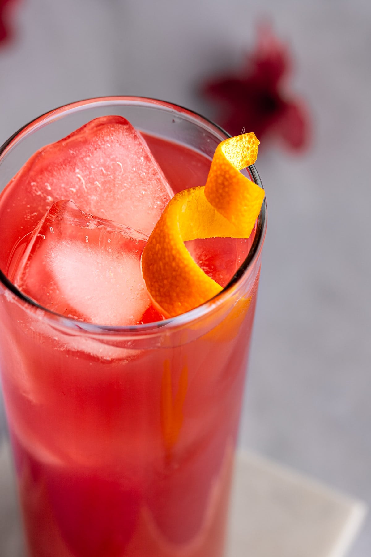 Up close view of a reddish-pink madras cocktail, garnished with an orange peel twist.