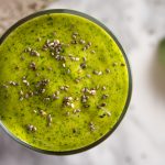 Up close, overhead view of a mango spinach smoothie, garnished with chia seeds.