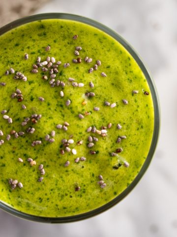 Up close, overhead view of a mango spinach smoothie, garnished with chia seeds.