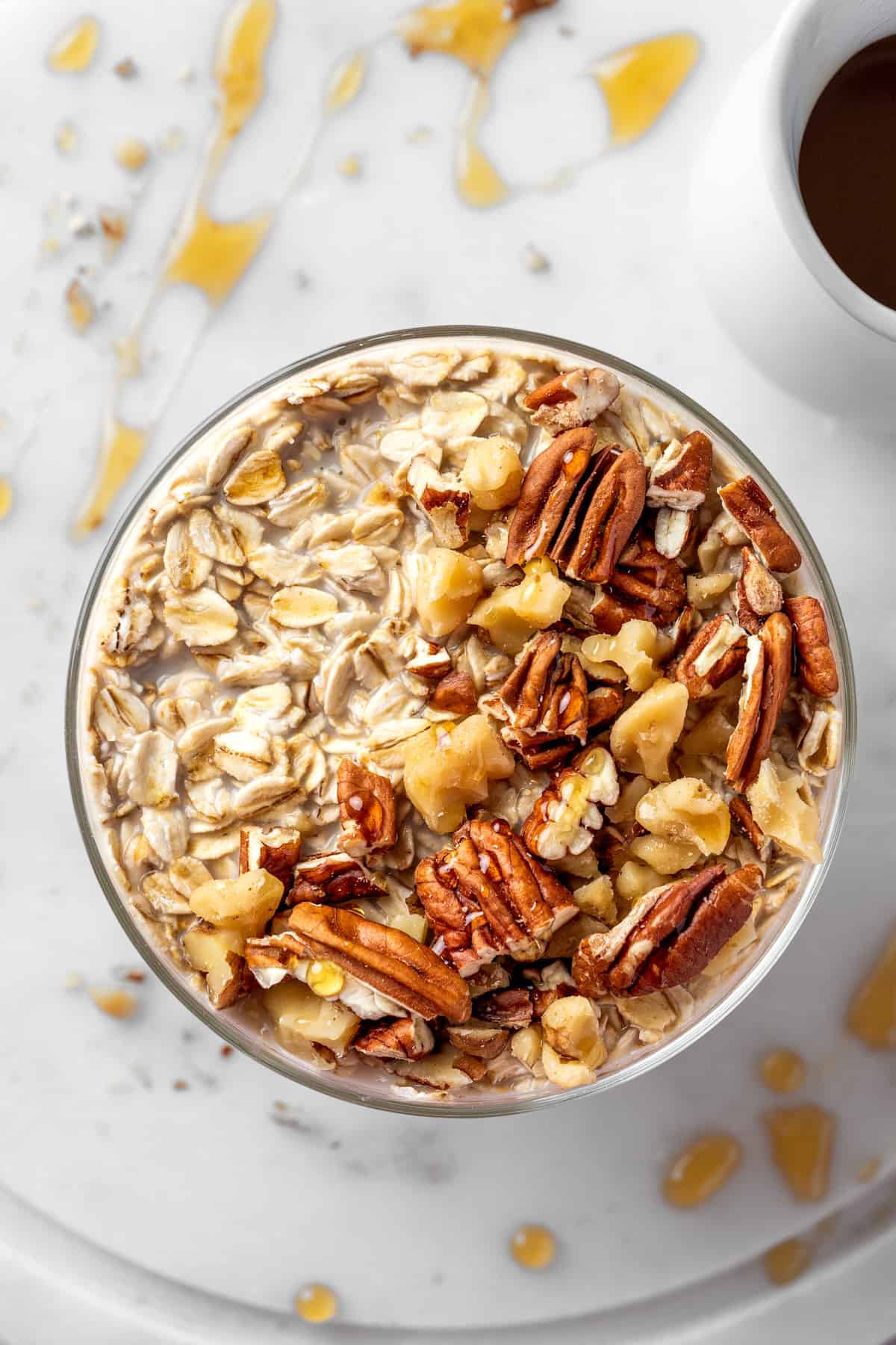 A bowl of maple brown sugar overnight oats topped with toasted nuts and a drizzle of maple syrup.