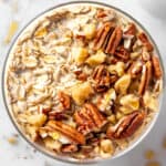 A bowl of maple brown sugar overnight oats topped with toasted nuts and a drizzle of maple syrup.