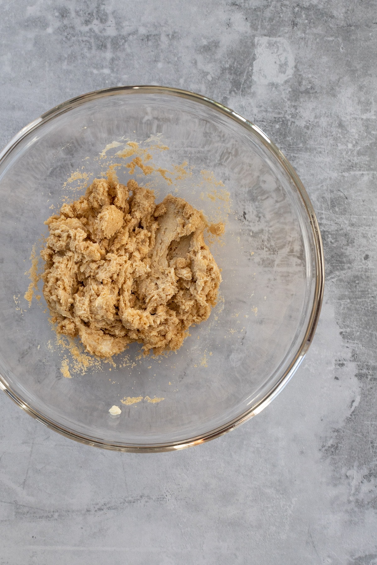 Brown sugar and butter creamed together in a glass mixing bowl.