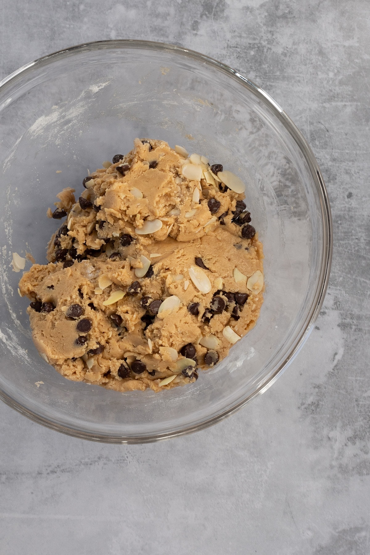 Cookie dough in a glass metal bowl, on a grey table.