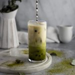 A spoon stirring the matcha milk tea to mix the green matcha and white almond milk together.