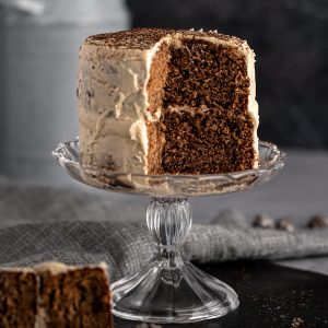 A mini layer cake with a slice missing, sitting on a small glass cake stand.