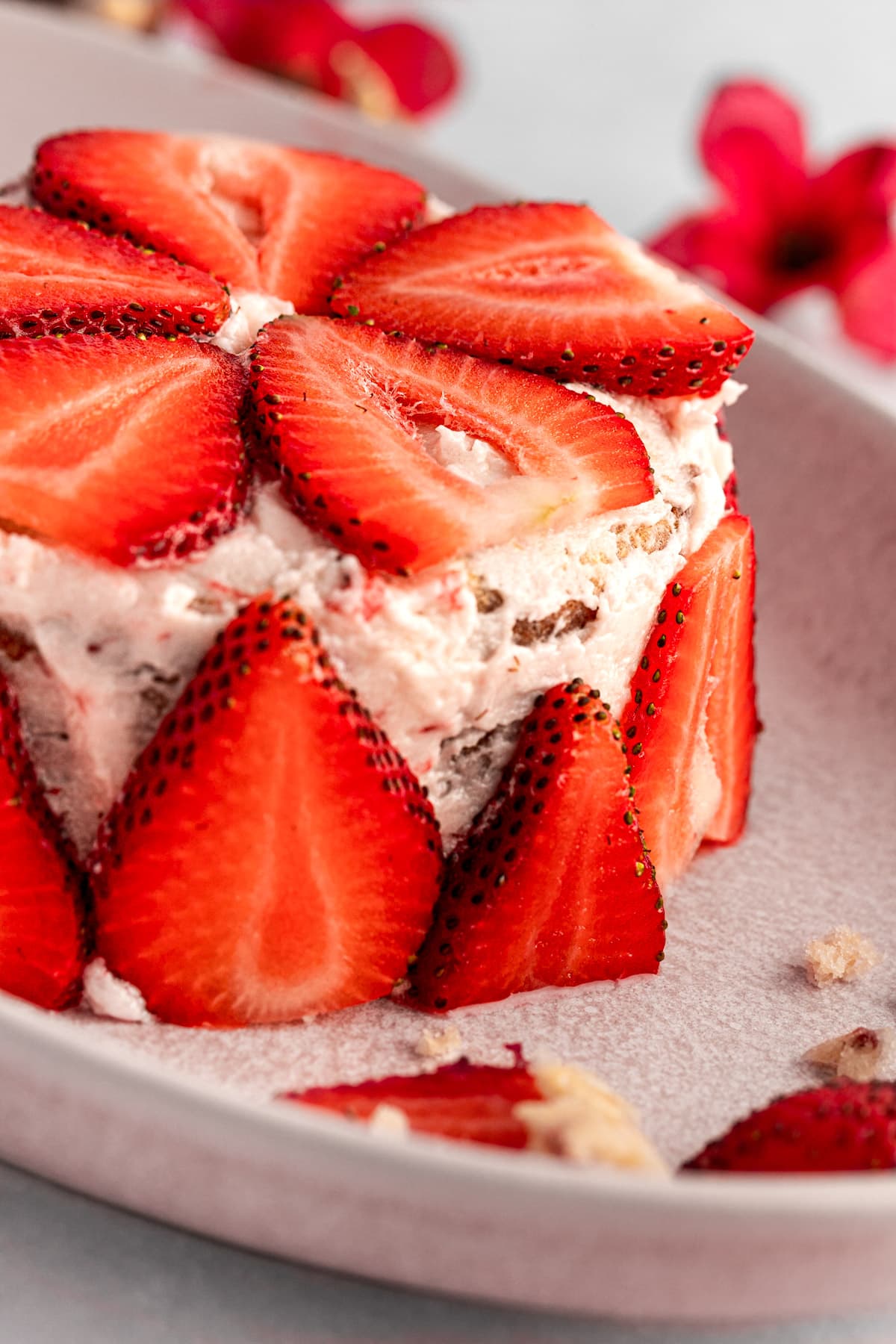Eye level view of a mini strawberry cake decorated with strawberry slices, sitting on a pink serving platter.