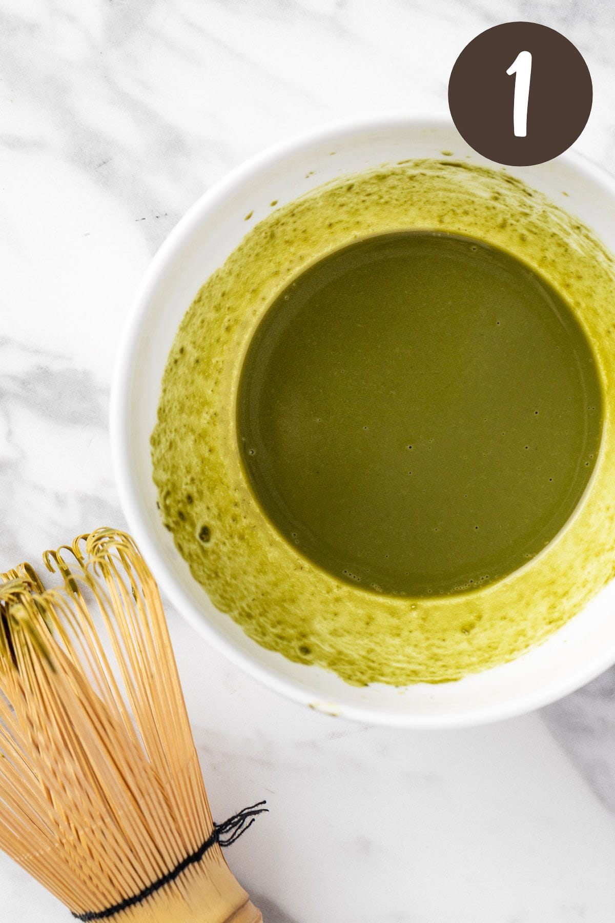 A process photo illustrating step 1: whisking the matcha powder and water together.