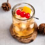 An old fashioned without bitters, garnished with maraschino cherries and an orange peel.