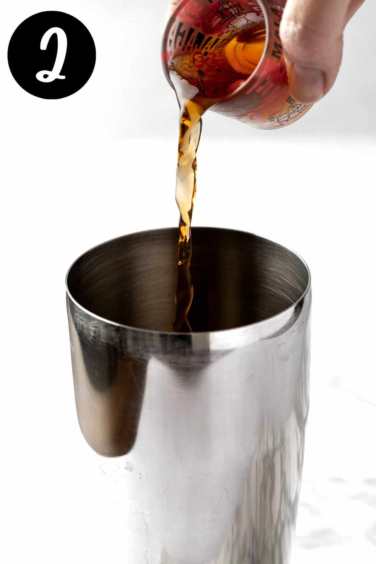 Pouring the Amaretto into a metal cocktail shaker.