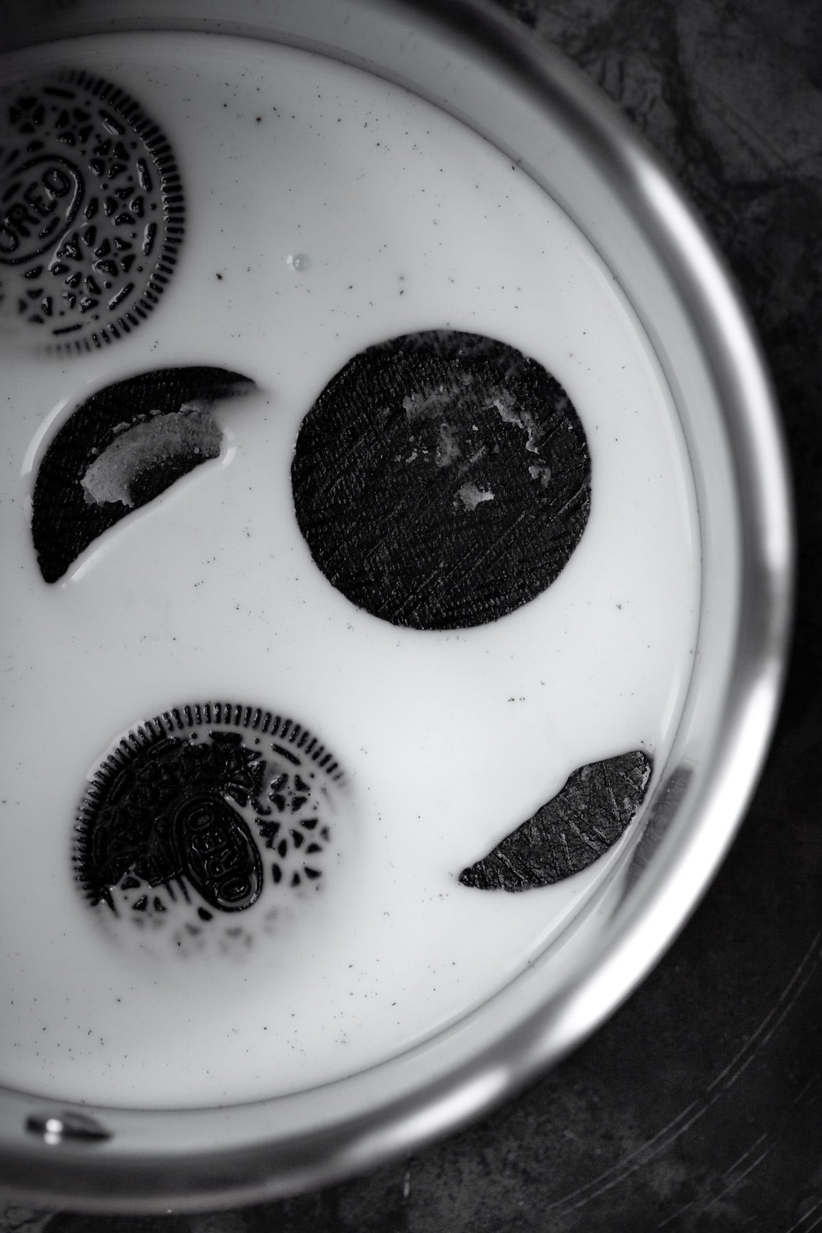 Large oreo cookies in milk in a saucepan, not yet fully dissolved.