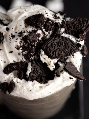 Overhead view of oreo hot chocolate topped with whipped cream and lots of smashed oreo cookie pieces.