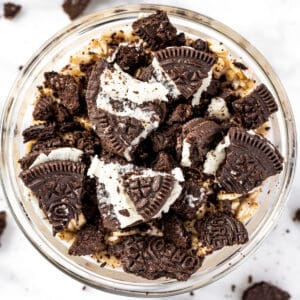 Oreo overnight oats in a small glass bowl, topped with chunks of Oreo cookies.