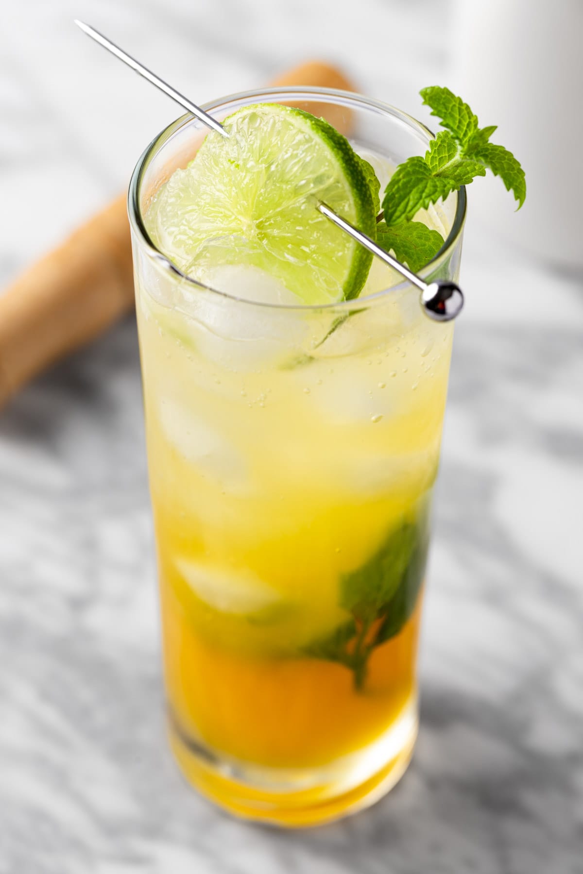 A passionfruit mojito mocktail garnished with a lime wheel and a sprig of mint.