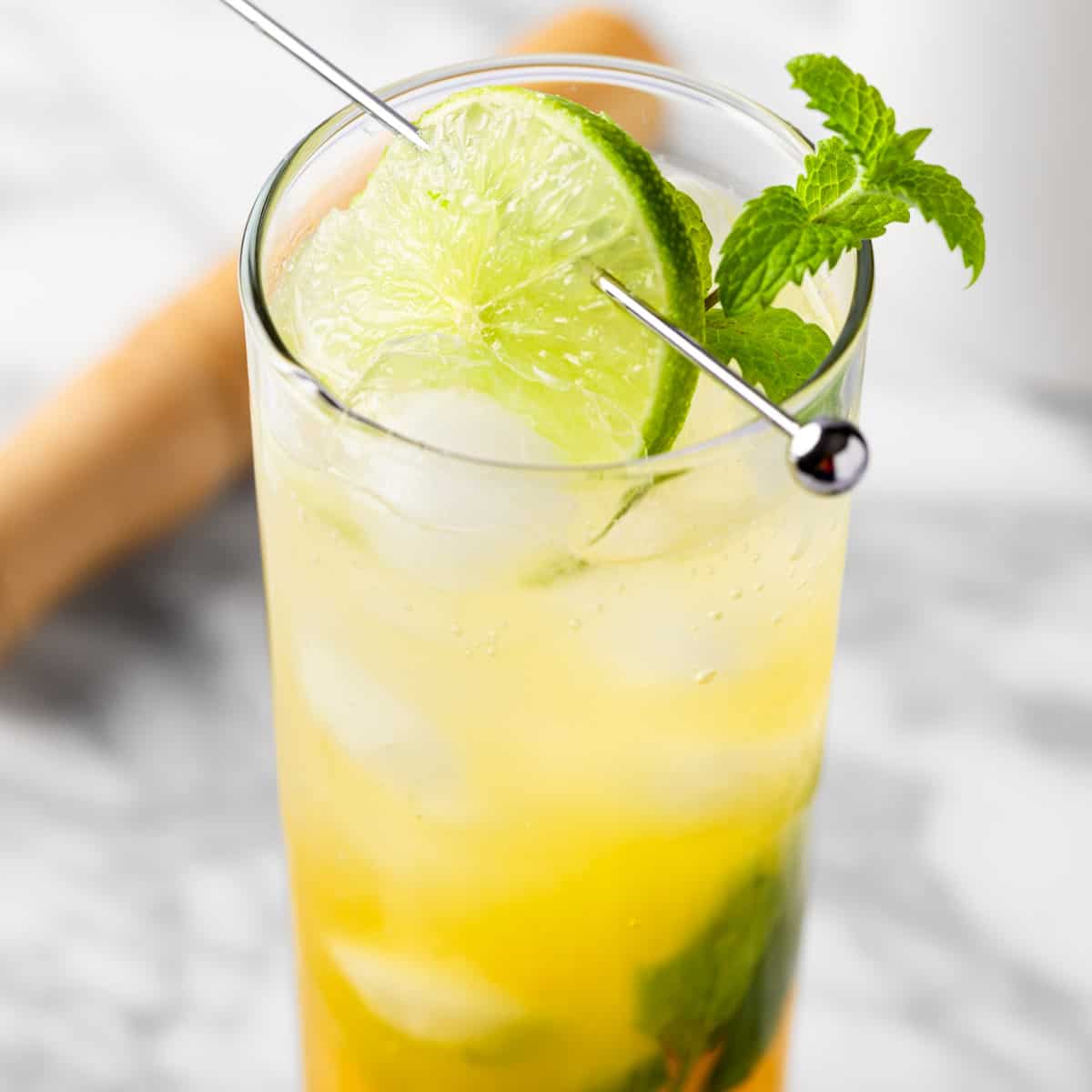 A passionfruit mojito mocktail garnished with a lime wheel and a sprig of mint.