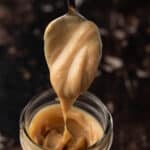 A spoonful of peanut butter ganache dripping down into a mason jar.