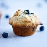 Up close side angle view of a pear and blueberry muffin with blueberries on the table beside