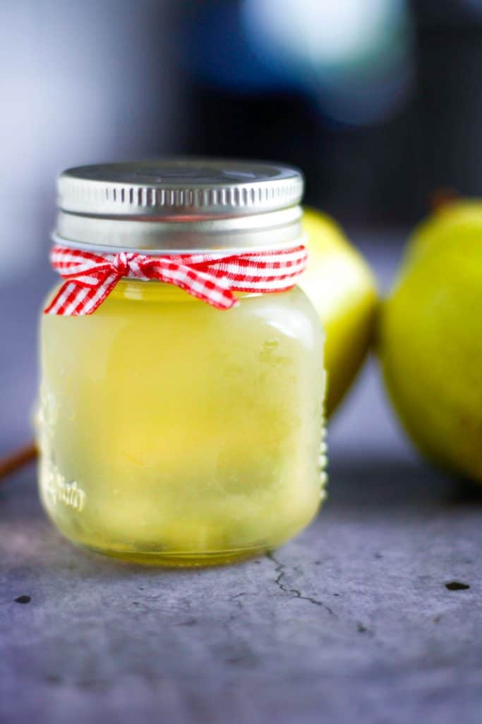small jar of pear simple syrup with red ribbon arount the lid
