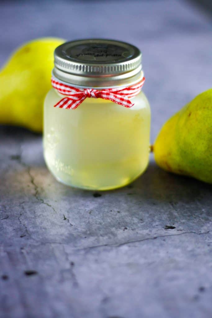 jar of pear simple syrup on the table with pears in the background