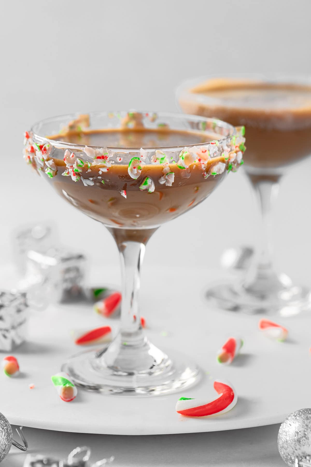 A a couple peppermint espresso martinis with a candy cane rim, next to scattered candy cane pieces.