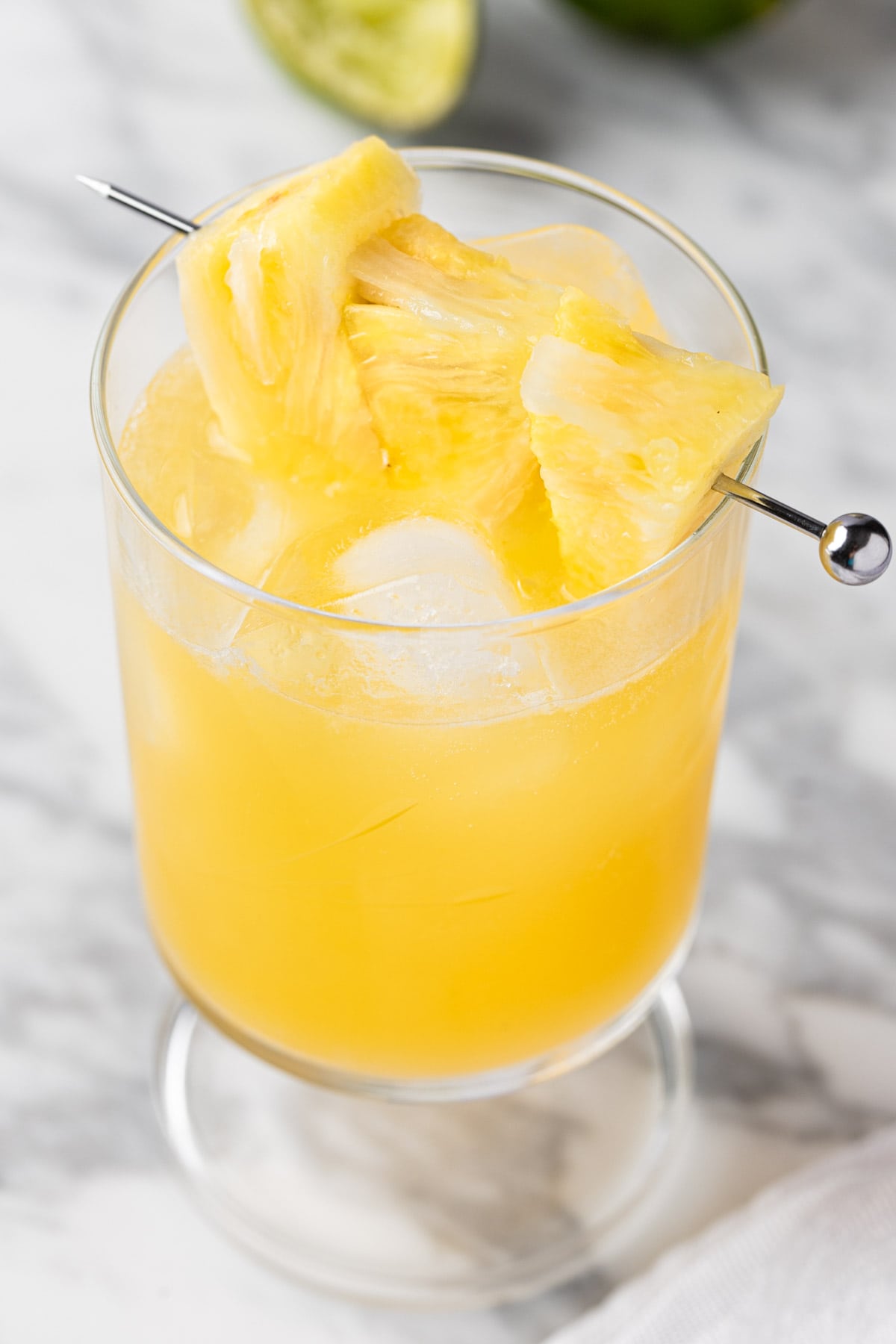 A pineapple gin cocktail garnished with pineapple slices.