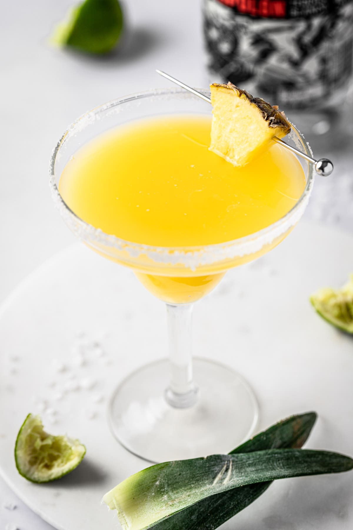 A pineapple orange margarita garnished with a pineapple slice and salted rim.