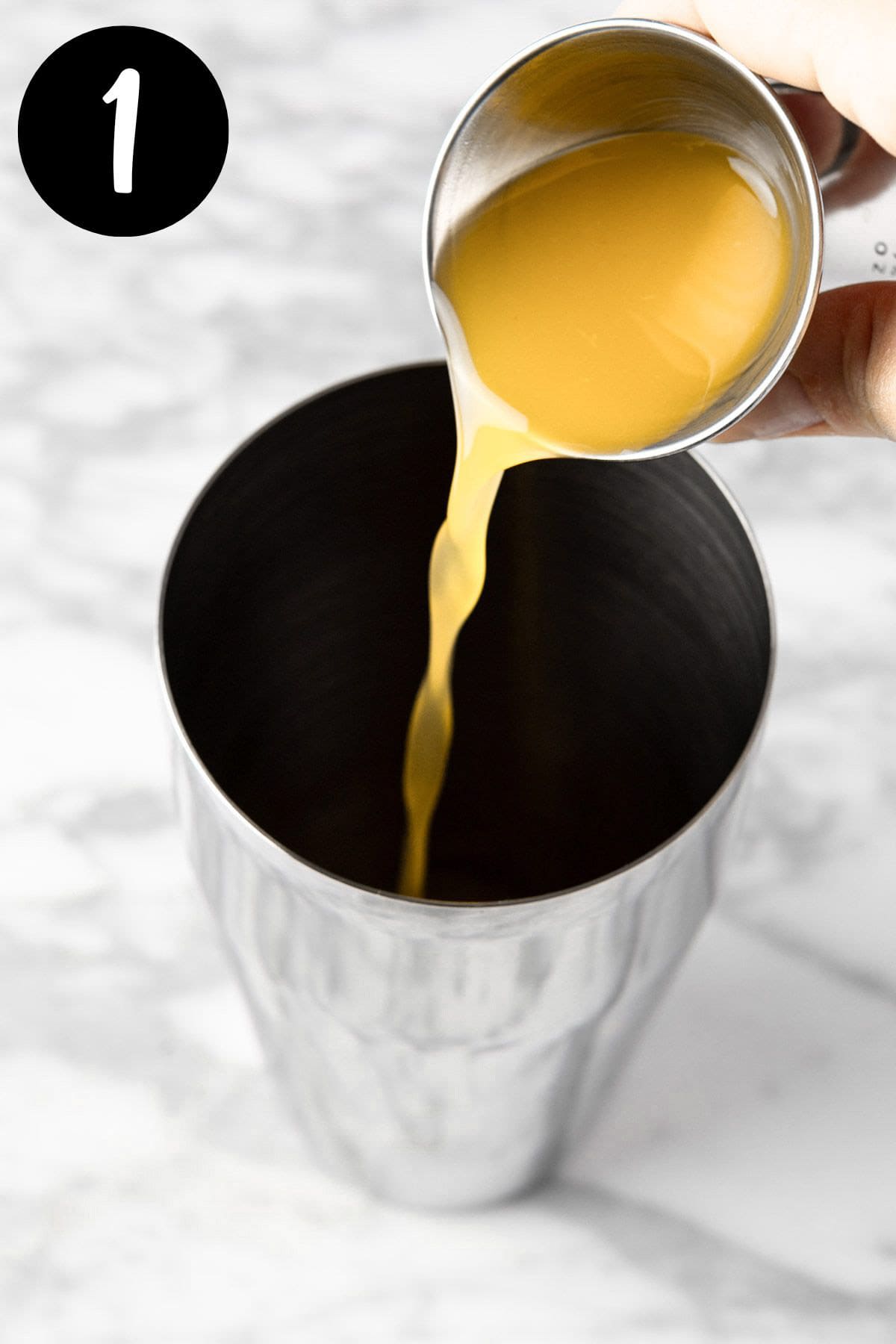 Pouring the pineapple juice into a cocktail shaker.