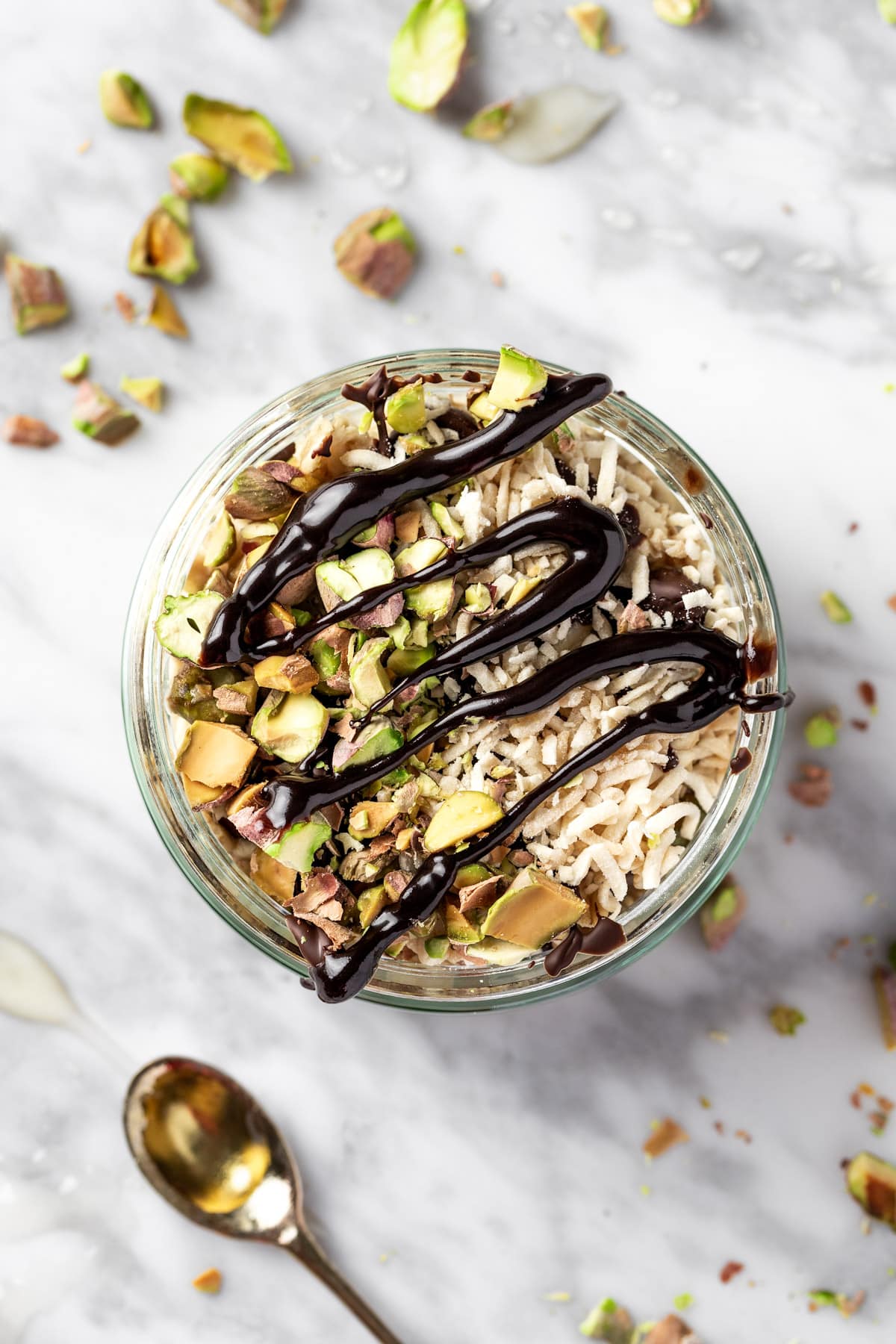 Pistachio overnight oats topped with dark chocolate, chopped pistachios and shredded coconut.