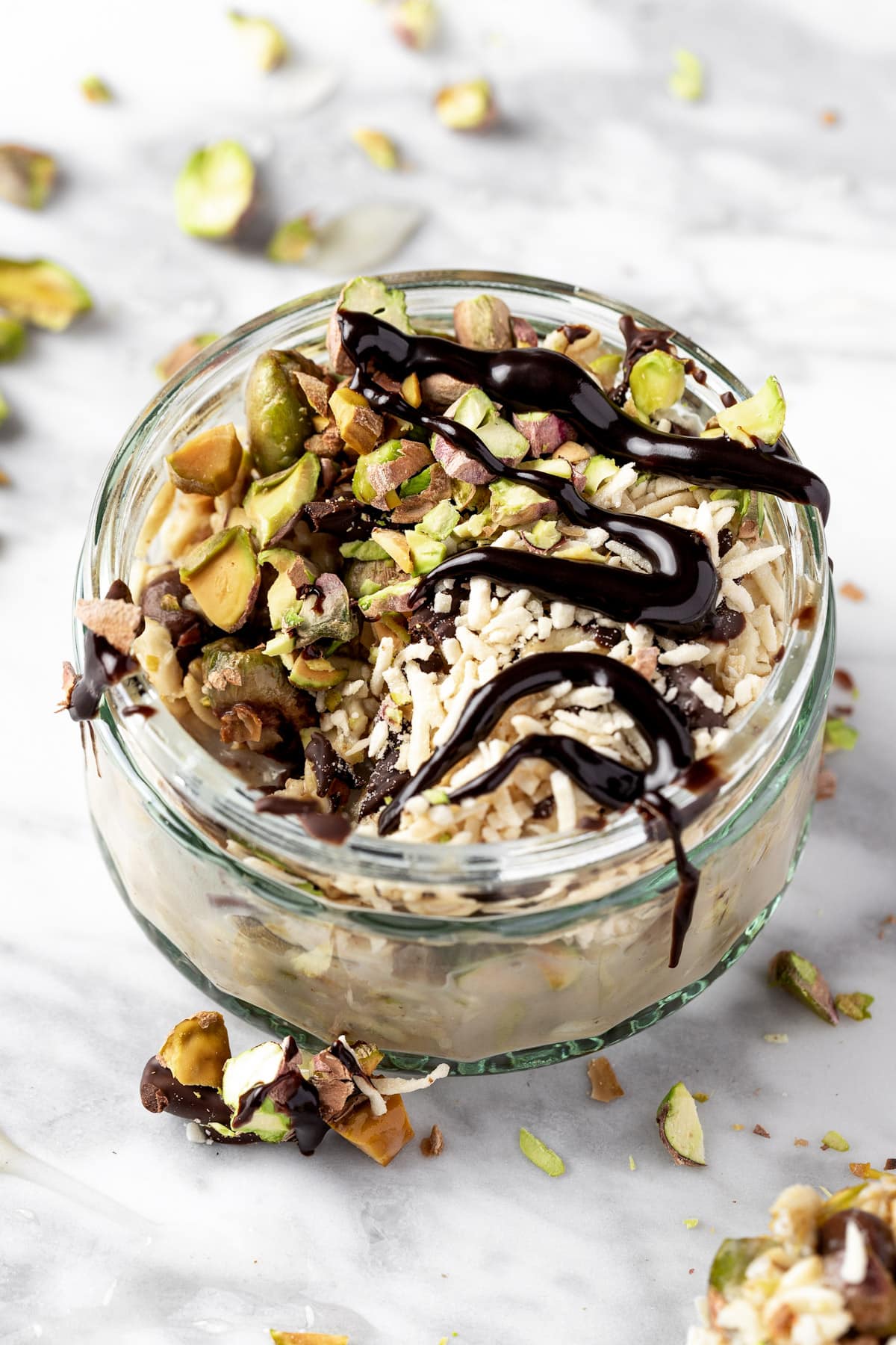 Pistachio overnight oats in a small glass jar, with a bite missing.