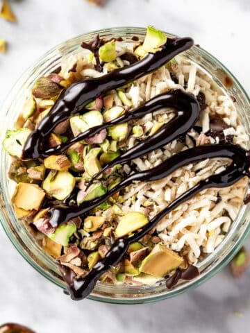 Pistachio overnight oats topped with dark chocolate, chopped pistachios and shredded coconut.