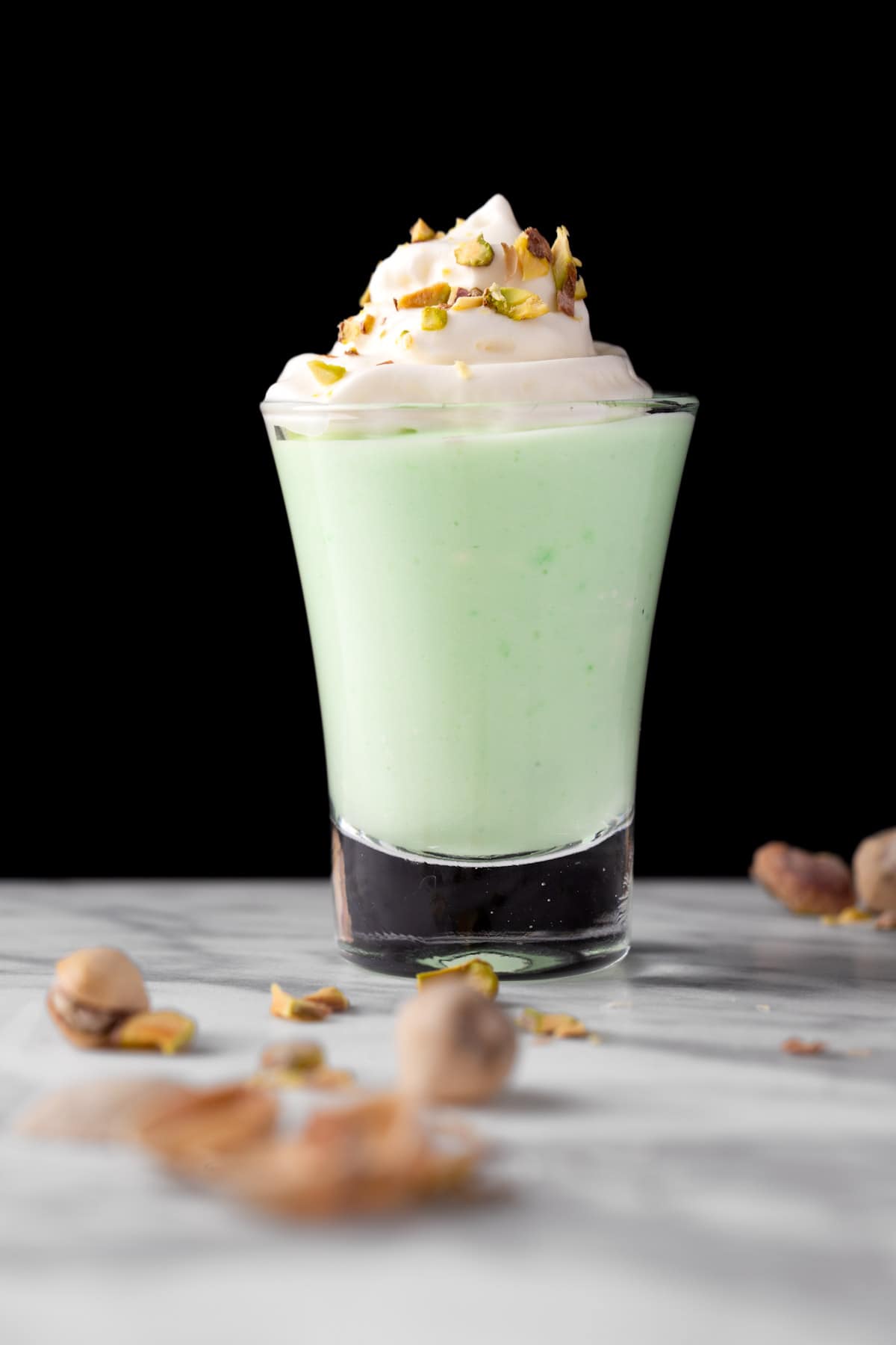 A green pistachio pudding shot on a black background.