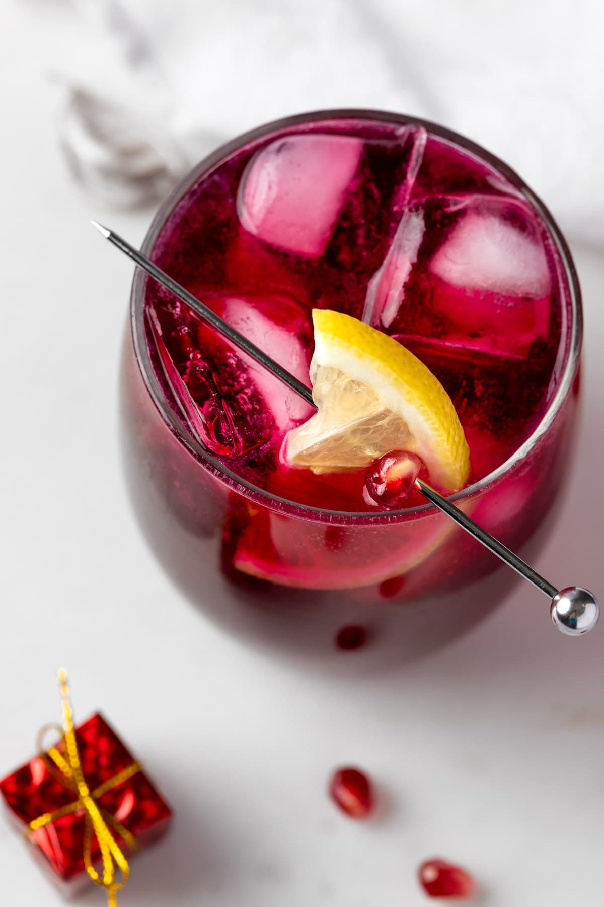 Overhead view of a pomegranate gin fizz garnished with lemon.