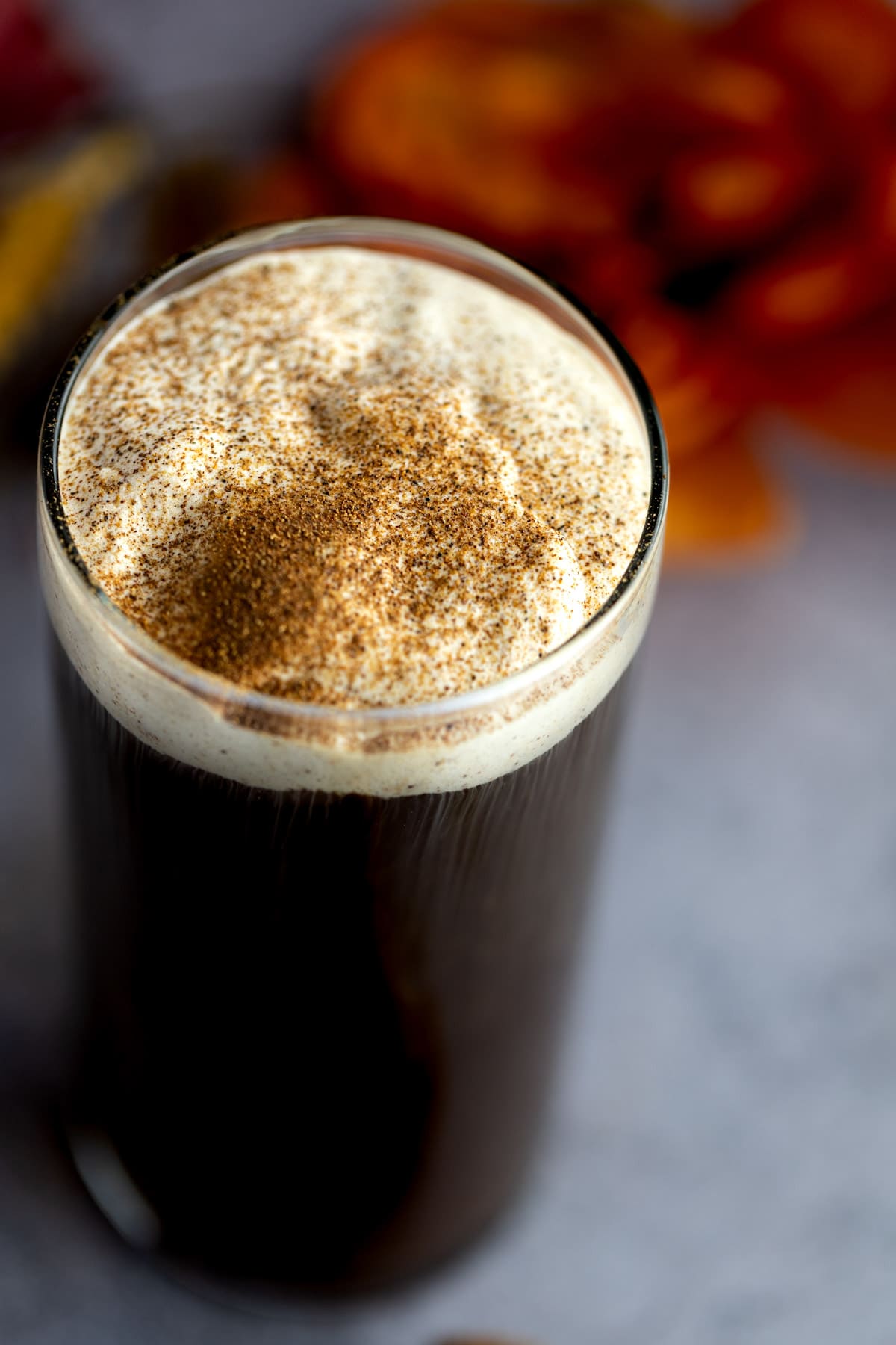 Close up photo of pumpkin cold foam on top of a black coffee, with pumpkin spice sprinkled on top of the foam.