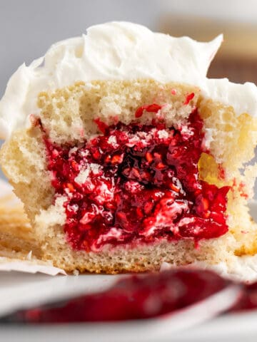 A white cupcake cut in half, filled with raspberry cupcake filling.