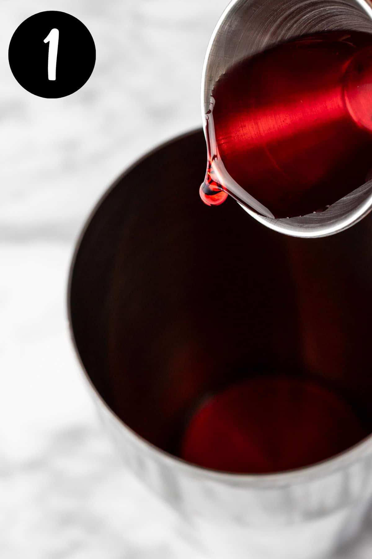 Pouring the raspberry syrup into a cocktail shaker.