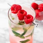 A raspberry mojito mocktail garnished with fresh raspberries and mint leaves.