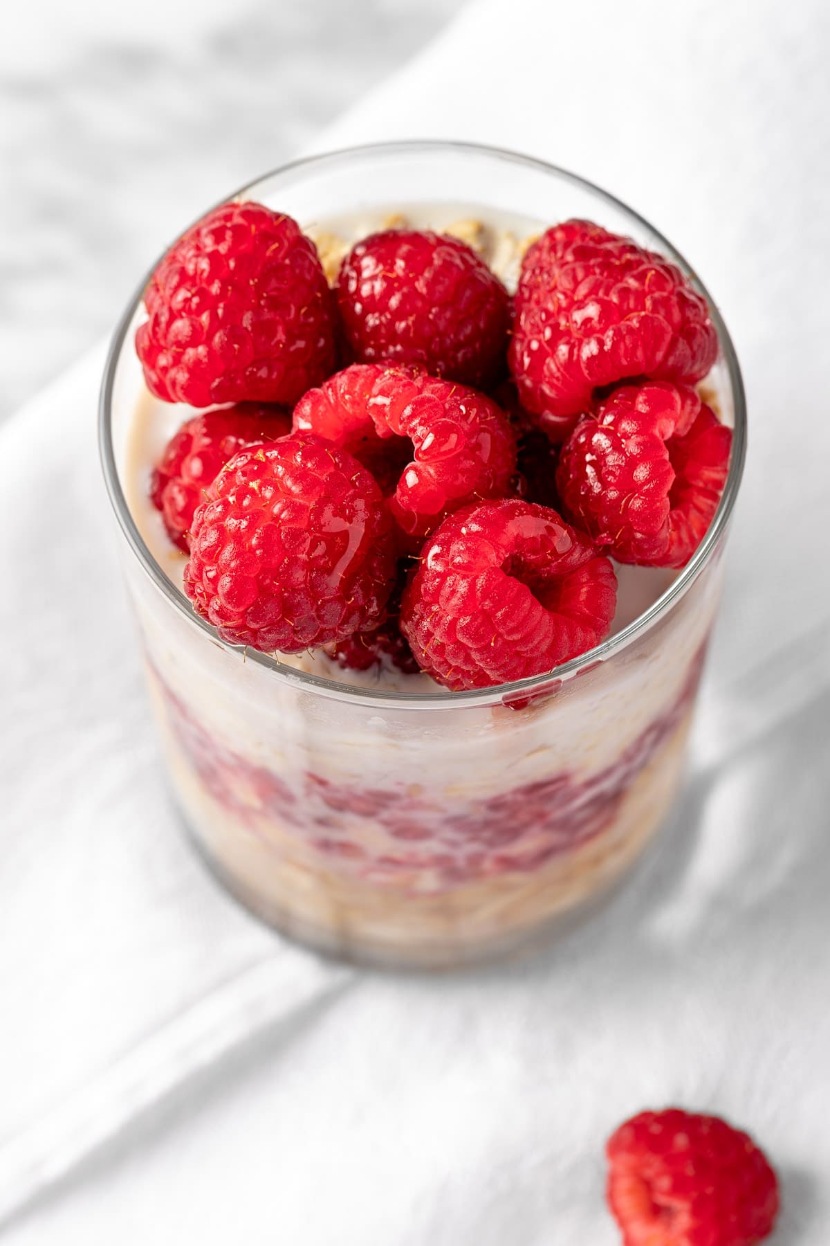 Overhead view of a jar of raspberry oats on a white background.