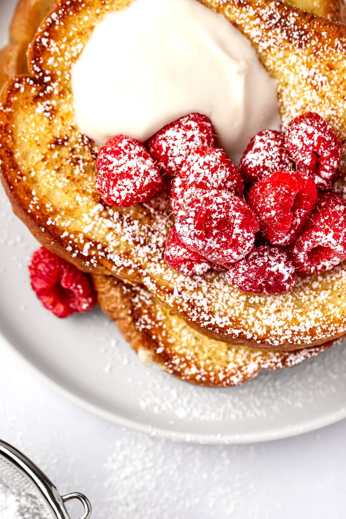 Overhead view of rumchata french toast sprinkled with powdered sugar, on a round white plate.