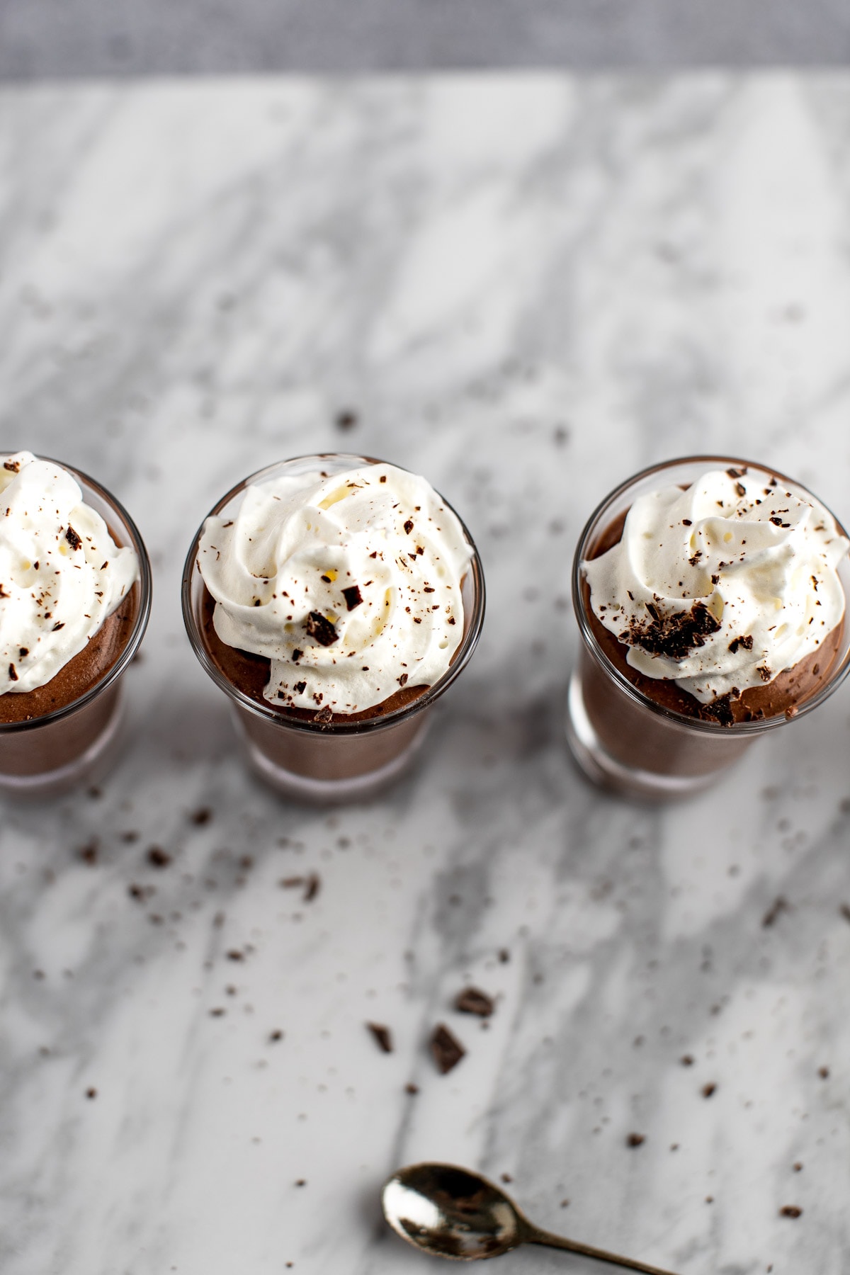An overhead view of three rumchata pudding shots topped with whipped cream and chocolate shavings.
