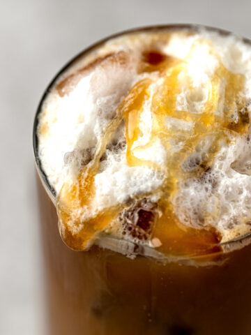 Salted caramel cold foam on top of a an iced coffee drink, with an extra drizzle of salted caramel sauce.