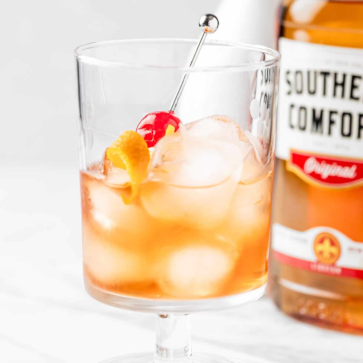 A Southern Comfort Old Fashioned Cocktail garnished with a cherry and orange peel twist.