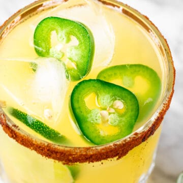 Overhead view of a spicy margarita garnished with sliced jalapenos.