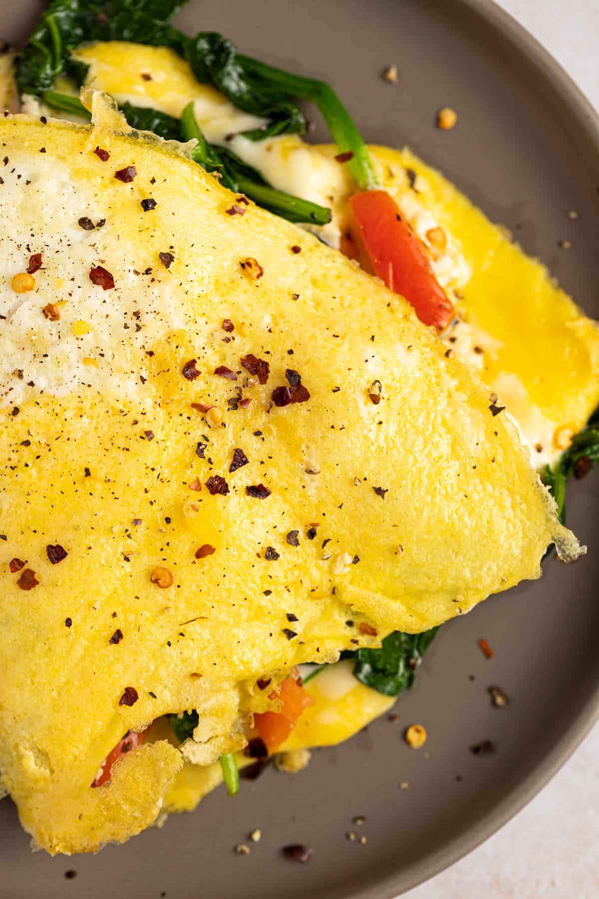 Up close view of a spinach & feta omelette topped with red pepper flakes.