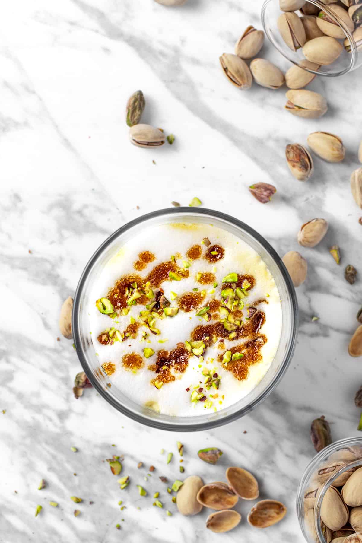 Overhead view of a starbucks pistachio latte topped with brown butter brown sugar topping and crushed pistachios.