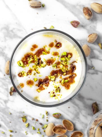 Overhead view of a starbucks pistachio latte topped with brown butter brown sugar topping and crushed pistachios.