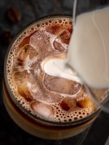 Starbucks sweet cream cold foam being poured on top of an iced coffee latte.