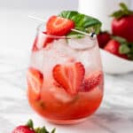 A strawberry basil mocktail garnished with fresh basil leaves and strawberry slices.