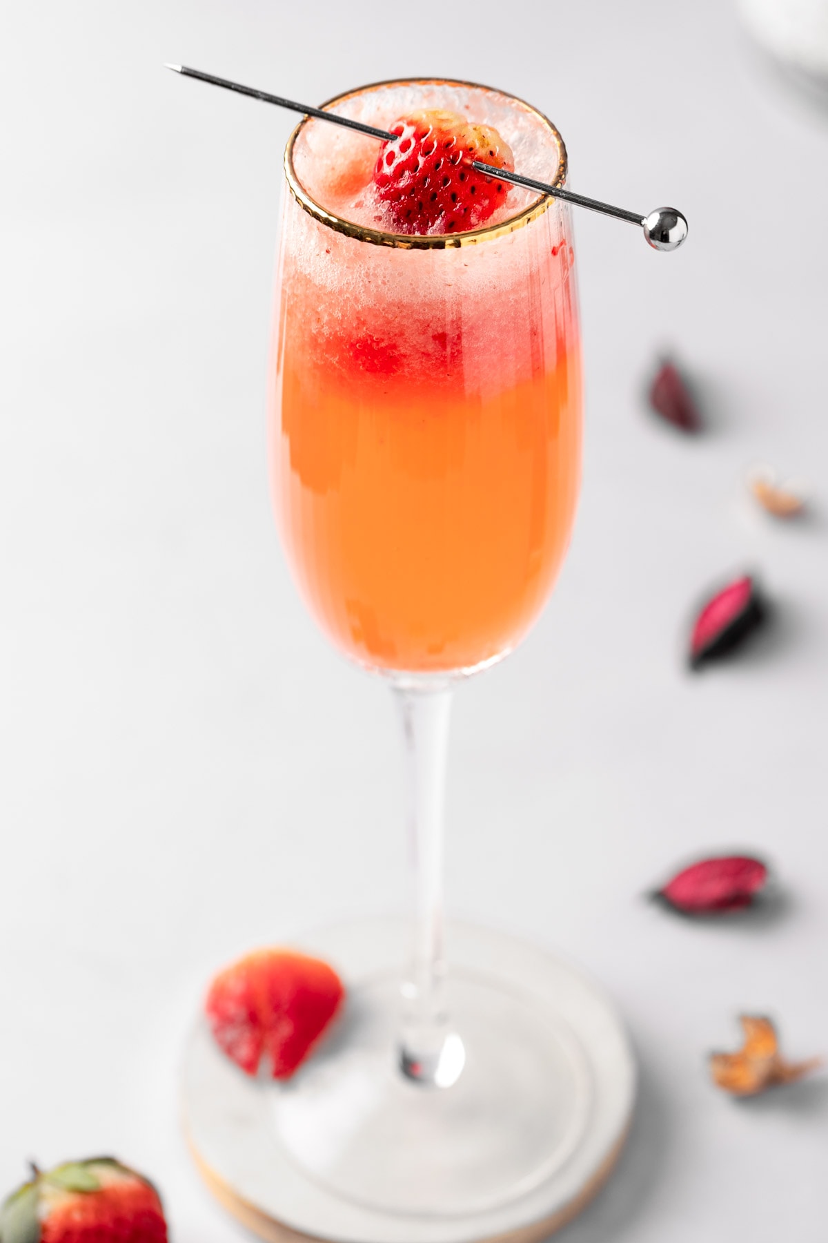 A strawberry bellini with prosecco, garnished with a strawberry slice.